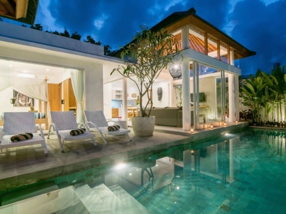 leasehold villa Berawa swimming pool at night with loungers and tropical landscaping